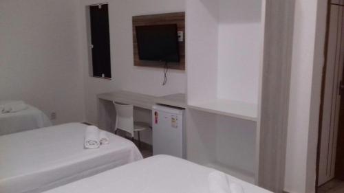 a room with two beds and a desk and a television at Urbano's Hotel in Canaã dos Carajás