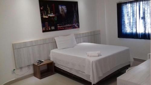 a bedroom with a white bed and a window at Urbano's Hotel in Canaã dos Carajás