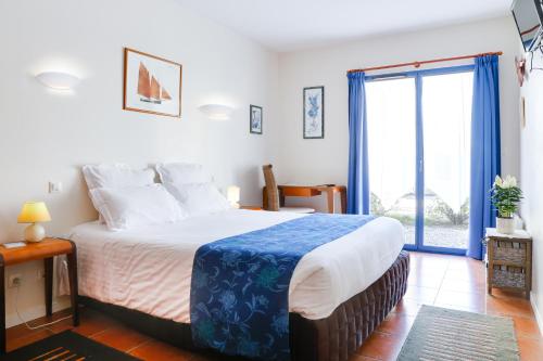 ein Schlafzimmer mit einem großen Bett und einem großen Fenster in der Unterkunft Hôtel Le Chevalier Gambette in Saint-Armel
