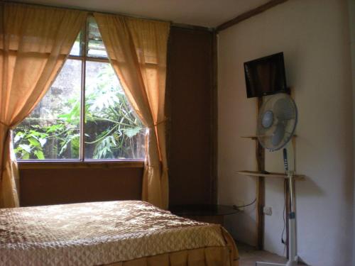 1 dormitorio con 1 cama y ventana con ventilador en Lodge El Barco, en Esterillos