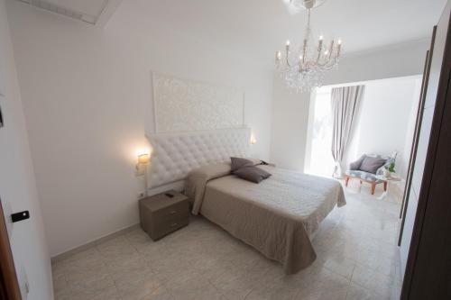 Habitación blanca con cama y lámpara de araña. en Hotel Imperiale, en Terzigno