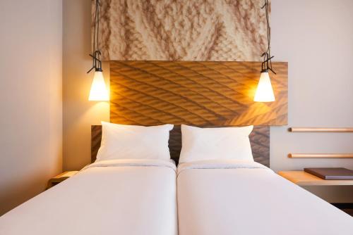 two beds in a hotel room with lights above them at ibis Jerusalem city Center - An AccorHotels Brand in Jerusalem