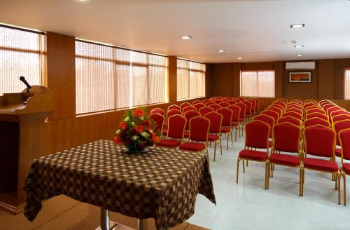 a conference room with a table and red chairs at Hotel Gopalapuram International in Pollāchi