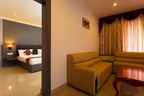 a hotel room with a couch and a bed at Hotel Gopalapuram International in Pollāchi