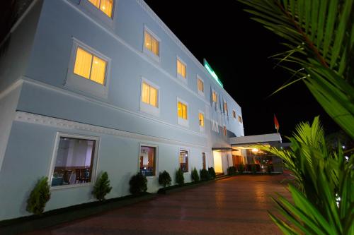 a large white building with lights on at night at Hotel Gopalapuram International in Pollāchi