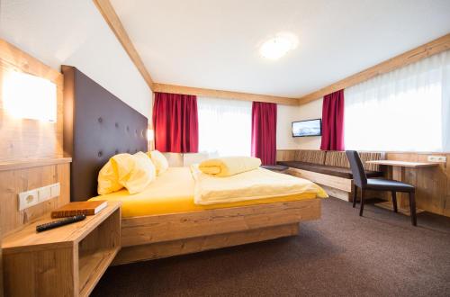 a bedroom with a bed with a desk and a chair at Gästehaus Falkner Ignaz in Sölden