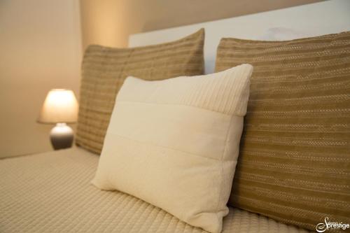 a white pillow sitting on a bed with two pillows at SalernoPrestige rooms in Salerno