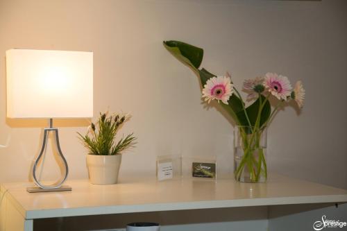 a vase of flowers on a table next to a lamp at SalernoPrestige rooms in Salerno