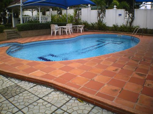 a swimming pool with a table and chairs and an umbrella at Lavender Lodge Hotel in Accra