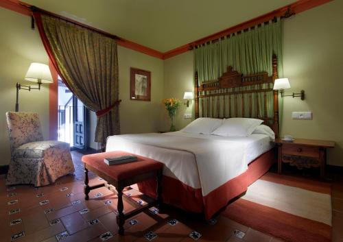 a bedroom with a large bed and a chair at Parador de Ubeda in Úbeda