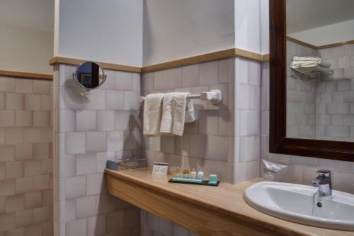 
a bathroom with a sink, mirror and towel rack at Parador de Ubeda in Úbeda
