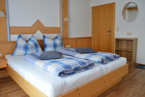a large bed with blue and white blankets and pillows at Gästehaus Huber in Leogang