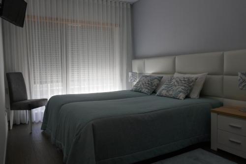 a bedroom with a large bed and a window at Two Churches Apartment in Leiria
