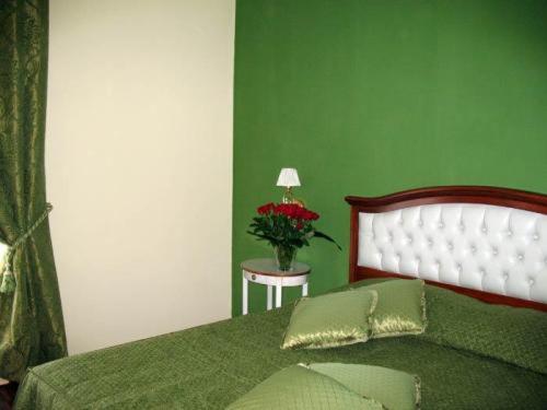 a green bedroom with a bed and a table with a vase of flowers at Hotel San Giorgio in Crotone