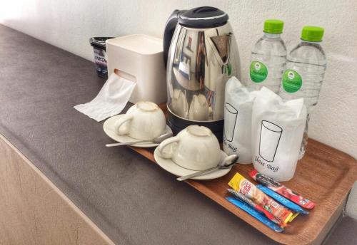 a counter with a tea pot and cups and bottles of water at River Nature Hotel in Suratthani
