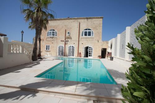 a swimming pool in front of a building at Villa Bernardette in Xagħra