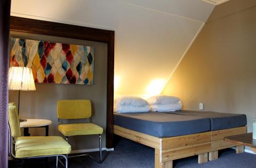 a room with a bed and a chair and a table at B&B "de Wingerd" in Bruchterveld