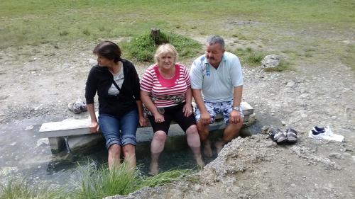 three people sitting on a bench in the water at Chata Adavy in Liptovský Ján