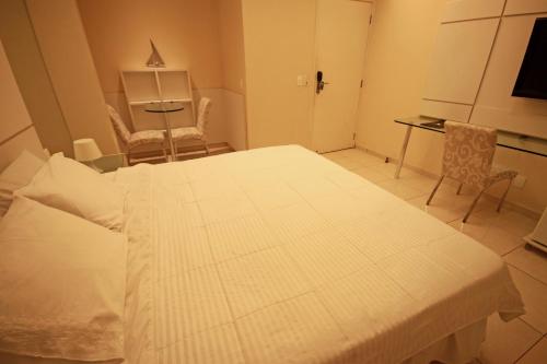 a bedroom with a bed and a table and chairs at Hotel Jangadeiro in Recife