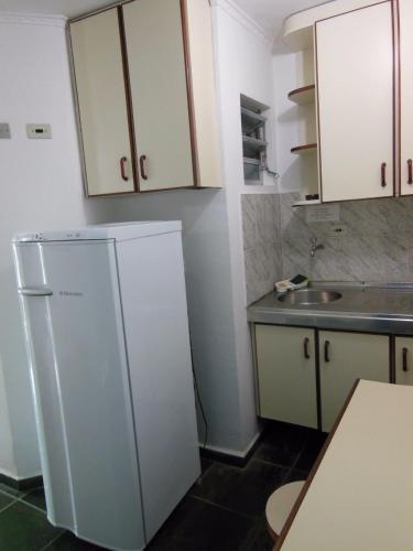 a kitchen with a white refrigerator and a sink at Praia Sul Studios in Peruíbe