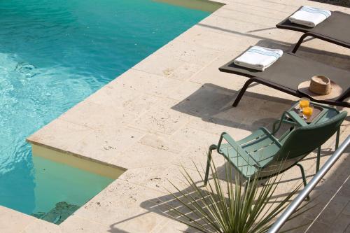 a chair and table next to a swimming pool at La Maison du Passage - Chambres - Suites premium, Spa, Piscine et Restaurant in Martignargues