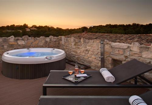 a jacuzzi tub on a deck with a table with wine glasses at La Maison du Passage - Chambres - Suites premium, Spa, Piscine et Restaurant in Martignargues