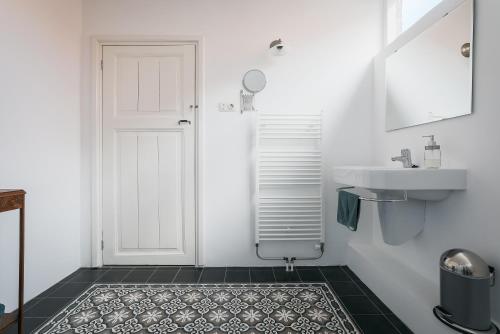 a bathroom with a white door and a sink at De Verwennerie in Zierikzee