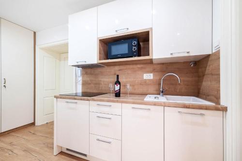 eine Küche mit weißen Schränken, einem Waschbecken und einem TV in der Unterkunft Rialto Luxury Apartment in Šibenik