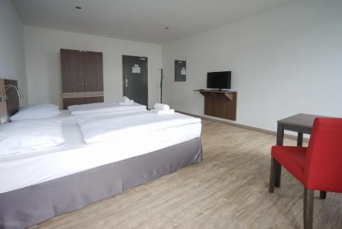a bedroom with a large bed and a red chair at Ruhr Inn Hotel in Hattingen