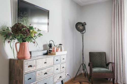 a room with a dresser with a television and a chair at De Verwennerie in Zierikzee
