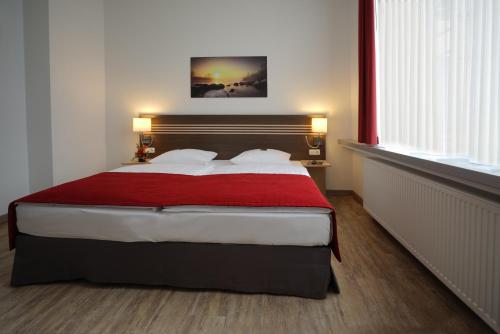 a bedroom with a large bed with a red blanket at Ruhr Inn Hotel in Hattingen