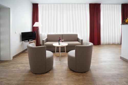 a living room with a couch and chairs and a table at Ruhr Inn Hotel in Hattingen