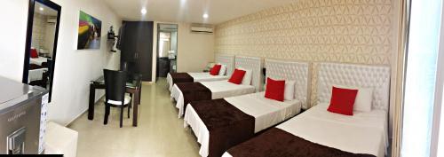 a row of beds in a room with red pillows at Hotel Boutique El Poblado in Neiva