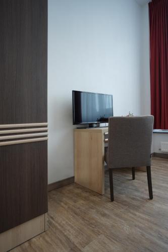 a room with a desk with a television and a chair at Ruhr Inn Hotel in Hattingen