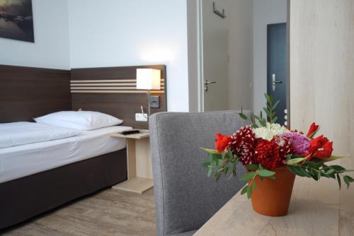 a bedroom with a bed and a vase of flowers on a table at Ruhr Inn Hotel in Hattingen