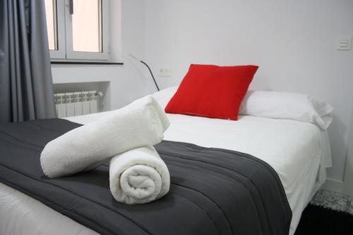 ein Bett mit weißen Handtüchern und einem roten Kissen in der Unterkunft Smart Tech Plaza Studio in Salamanca