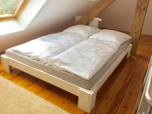 Bett mit weißer Bettwäsche und Kissen in einem Zimmer in der Unterkunft Ferienwohnung Rostock in Rostock
