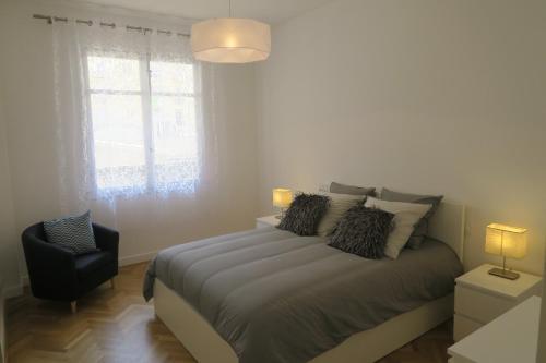 une chambre avec un lit avec une chaise et une fenêtre dans l'établissement Carré d’Or Appt 4 Pièces moderne et spacieux, à Nice