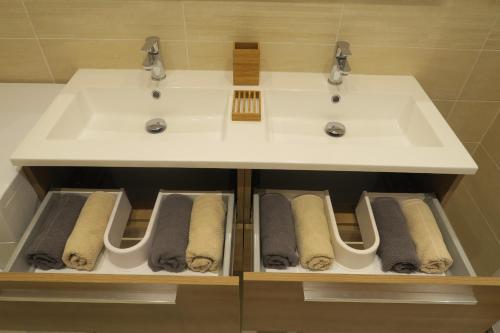 La salle de bains est pourvue d'un lavabo blanc et de serviettes. dans l'établissement Carré d’Or Appt 4 Pièces moderne et spacieux, à Nice