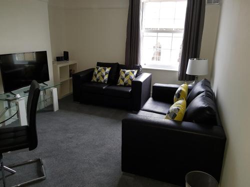 a living room with two black couches and a television at Braganza House in Portsmouth