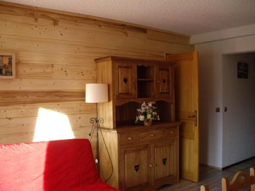 una camera da letto con pareti in legno, una sedia rossa e una lampada di Chalet Amandine a LʼAlpe-dʼHuez