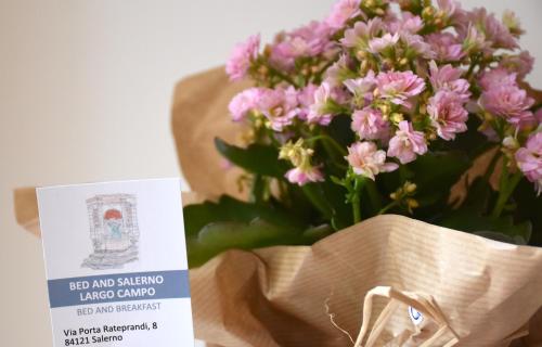 un ramo de flores rosas sentado junto a una tarjeta en Bed And Salerno - Largo Campo - Appartamento, en Salerno