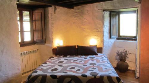 a bedroom with a bed in a room with windows at Casa do Solpor in La Teijeira