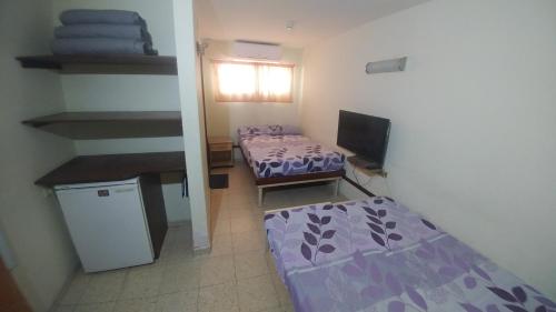a small room with two beds and a tv at Arava Hostel in Eilat
