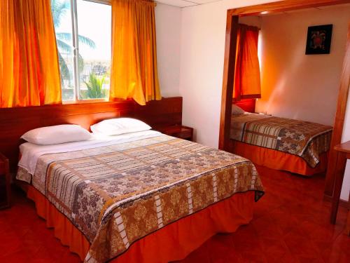 a hotel room with two beds and a mirror at Hostal Muyuyo in Puerto Ayora