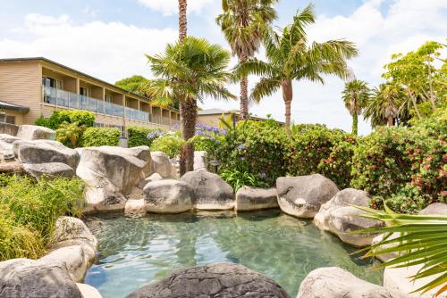 a pool of water with rocks and palm trees at Copthorne Hotel & Resort Bay Of Islands in Paihia