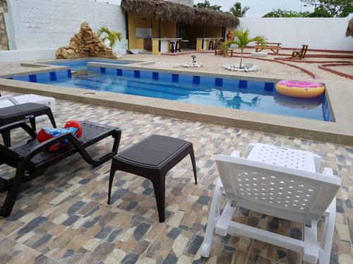 a pool with tables and chairs next to a building at Fogata Hostel in Salinas