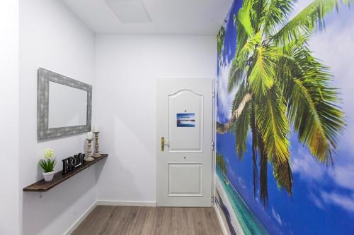 a hallway with a palm tree mural next to a door at Adorable urban suites in Las Palmas de Gran Canaria