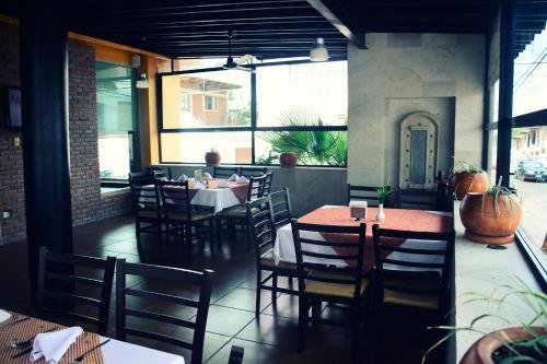 a dining room with tables and chairs and windows at Hotel San Carlos Tequisquiapan in Tequisquiapan