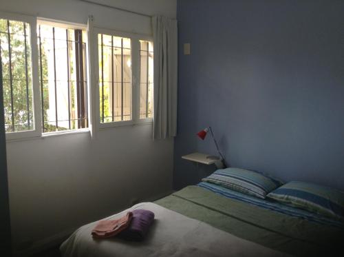 a bedroom with a bed and two windows at La Casa Roja Arroyito Rio in Rosario
